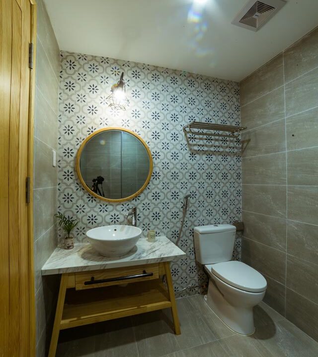 A bathroom in Danang, Vietnam equipped with a toilet, sink, and mirror.
