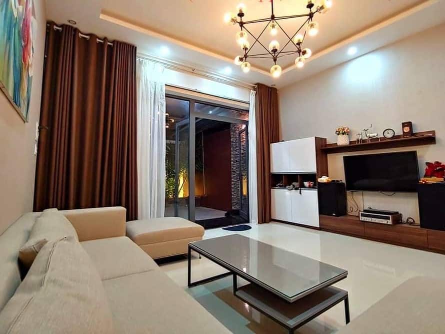 A living room with beige furniture and a chandelier located in Danang, Vietnam.