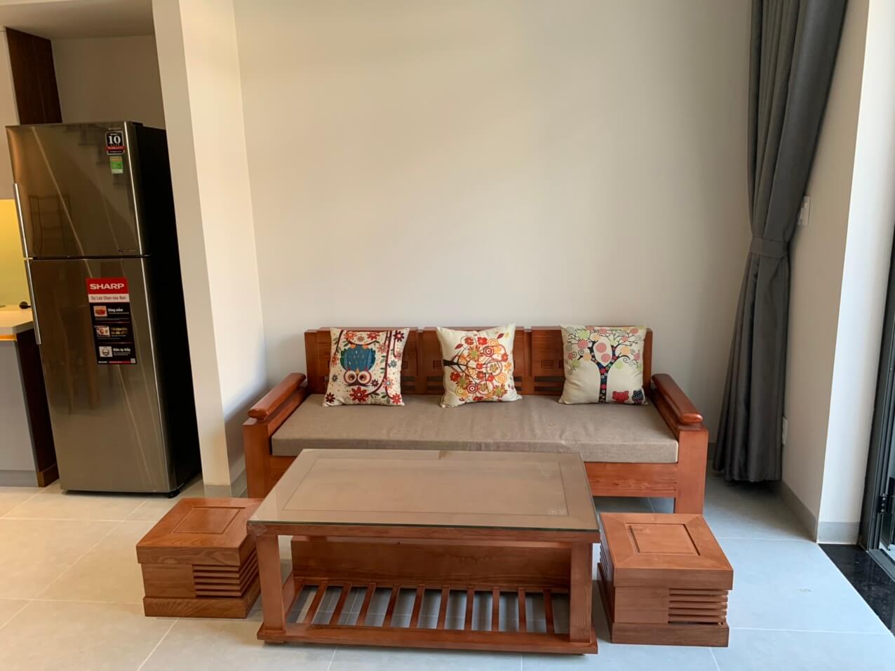 A living room with a couch, coffee table and refrigerator in Danang.