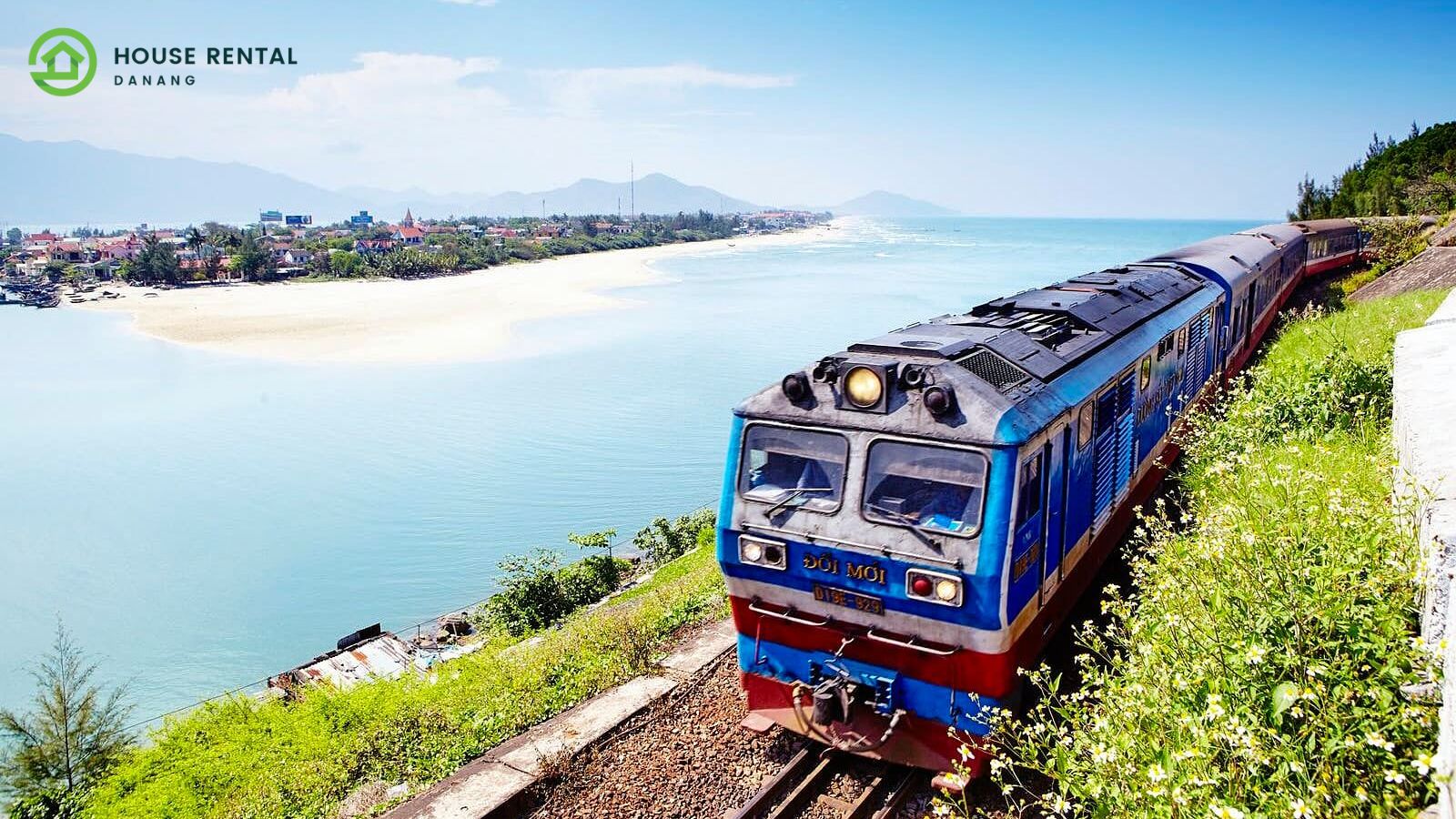 A blue train on the tracks near water.