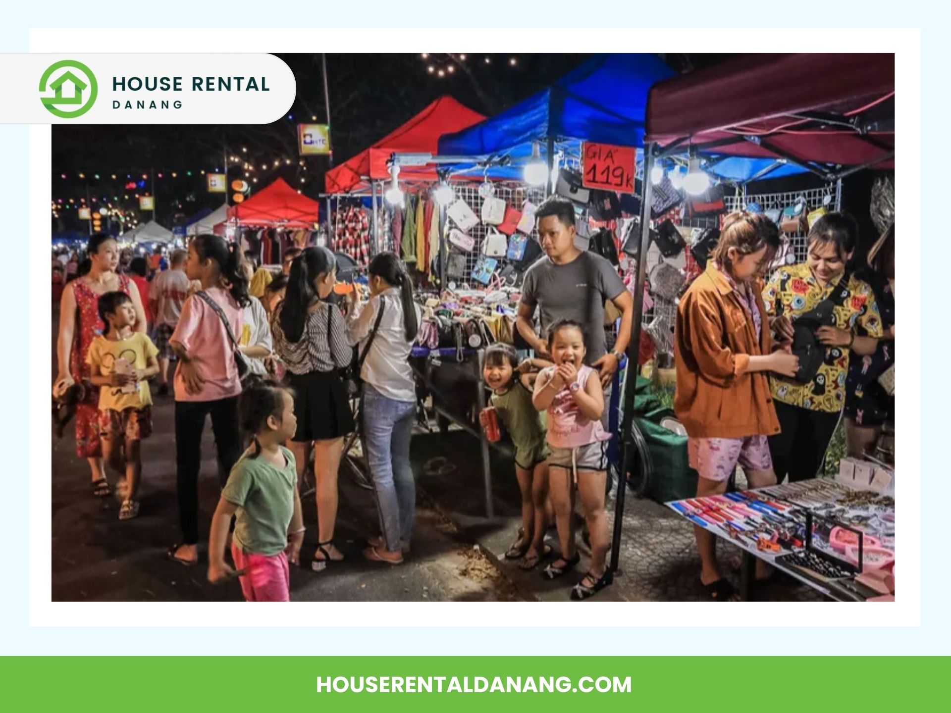 A bustling night market in Danang features people shopping at various brightly lit stalls. A family with three children is seen in the foreground, enjoying the vibrant scene. Colorful canopies and merchandise are displayed, adding to the lively atmosphere of these Night Markets in Danang.