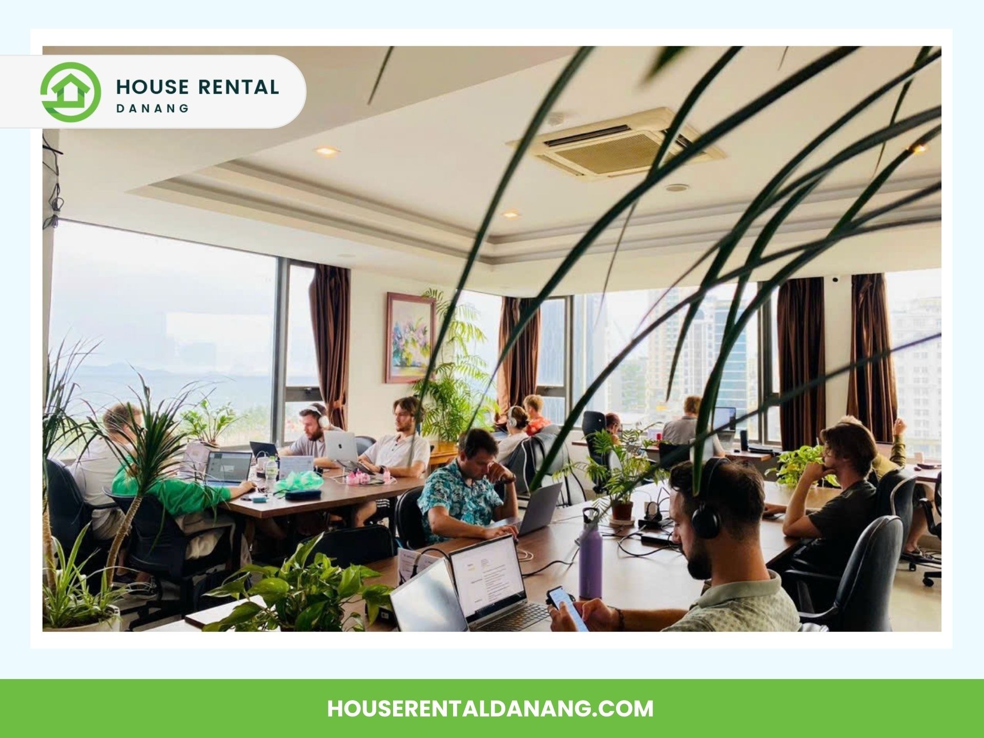 People working on laptops in a shared office space with large windows, plants, and a view of the city outside. Banner reads "House Rental Danang" with website houserentaldanang.com. Discover the best coworking spaces in Da Nang!