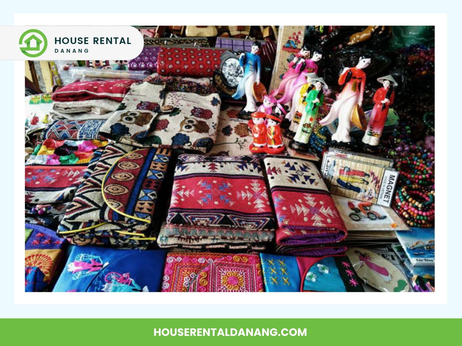 A vibrant display of colorful textiles, embroidered cloths, and small figurines arranged neatly on a market stall in Da Nang's bustling Han Market.