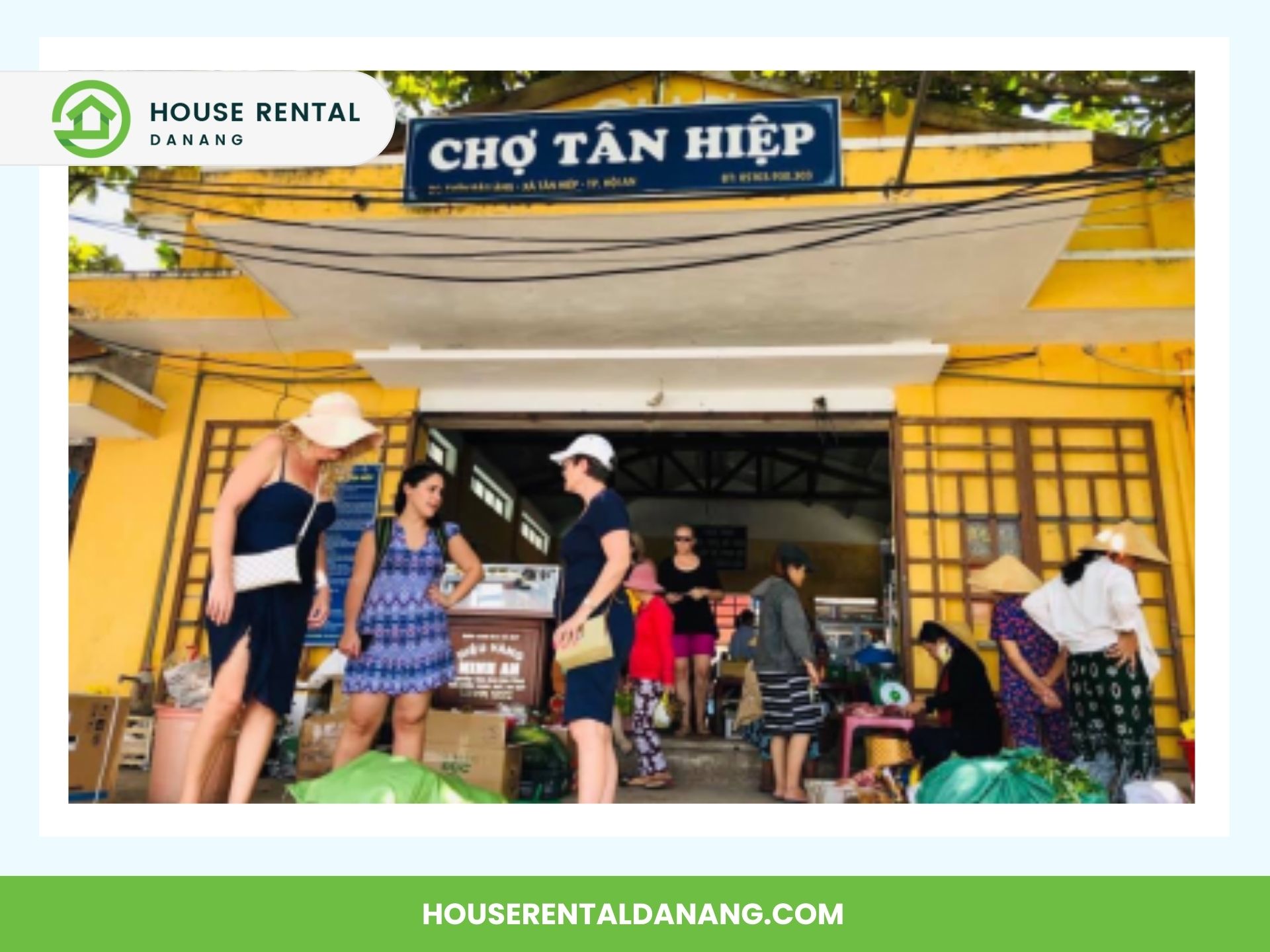 People shopping at Chợ Tân Hiệp market in Danang, Vietnam, surrounded by a variety of goods and produce. A sign with the market's name is visible above the entrance, offering travel reasons to explore nearby attractions like Cham Island.