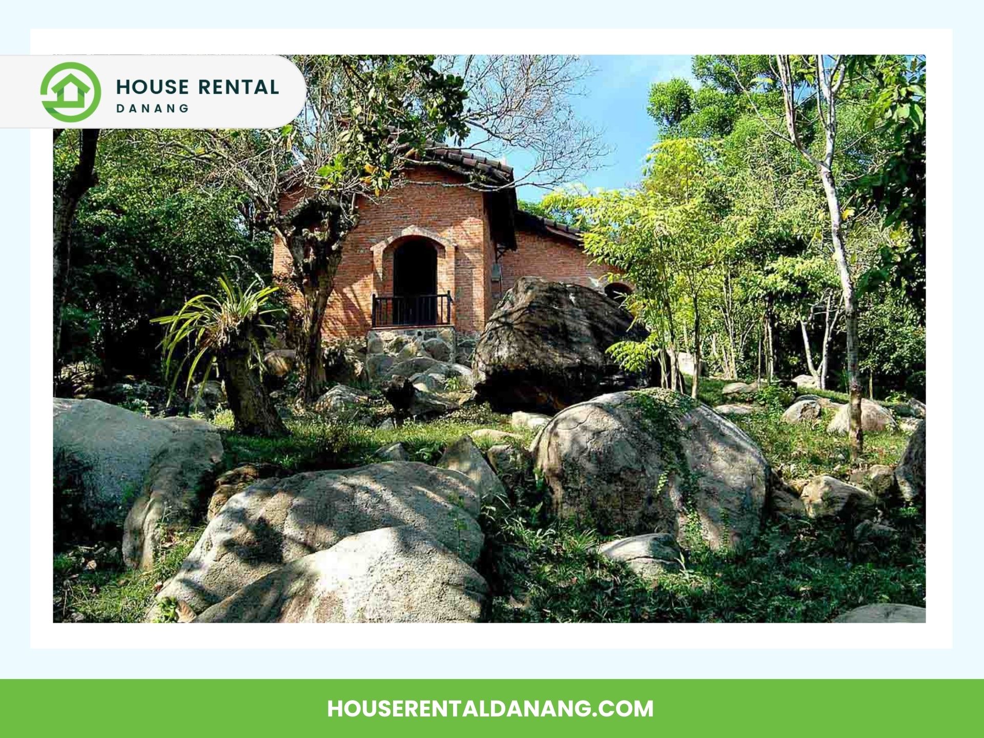 A brick house surrounded by large rocks and trees, with a logo and text reading "House Rental Da Nang" at the top and their website at the bottom. This scenic rental in Vietnam offers proximity to attractions like Dong Dinh Art Museum.