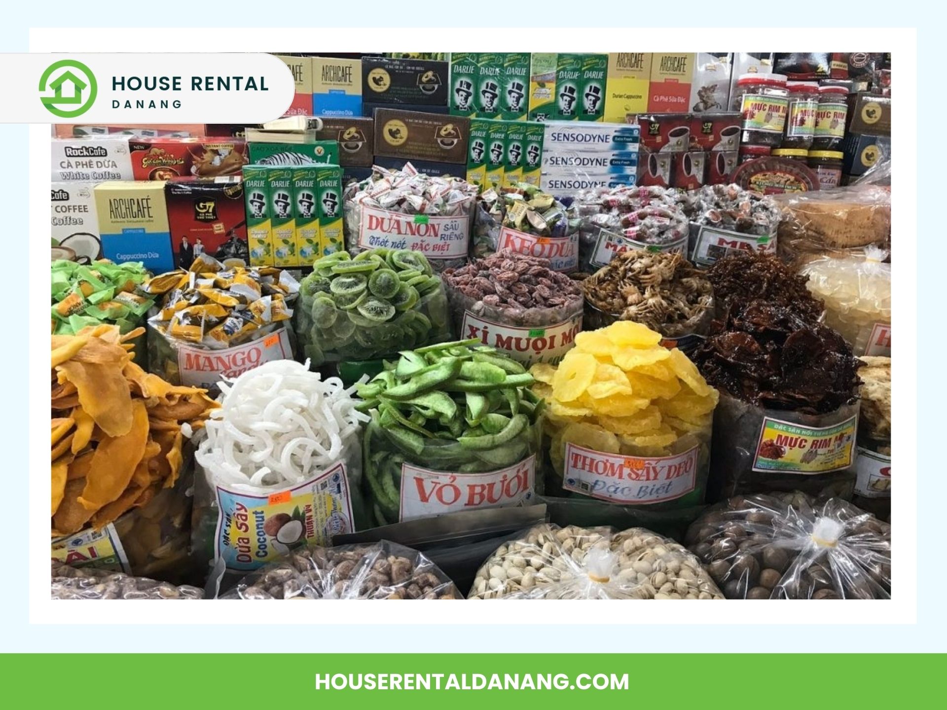 A market stall at the bustling Han Market Da Nang displays a variety of dried fruits and snacks in clear bags, with labels in Vietnamese. Shelves stocked with different packaged goods are seen in the background, capturing the essence of this vibrant coastal city's 2024 offerings.