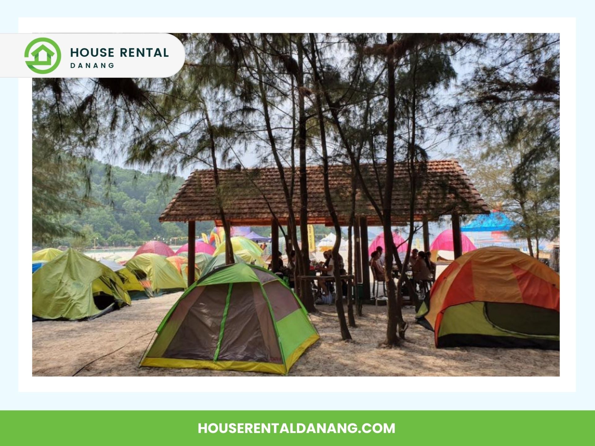 A scenic camping area with multiple tents set up under a shaded structure surrounded by trees, offering a serene escape near the renowned Hai Van Pass. The image features the logo and website name of "House Rental Danang.