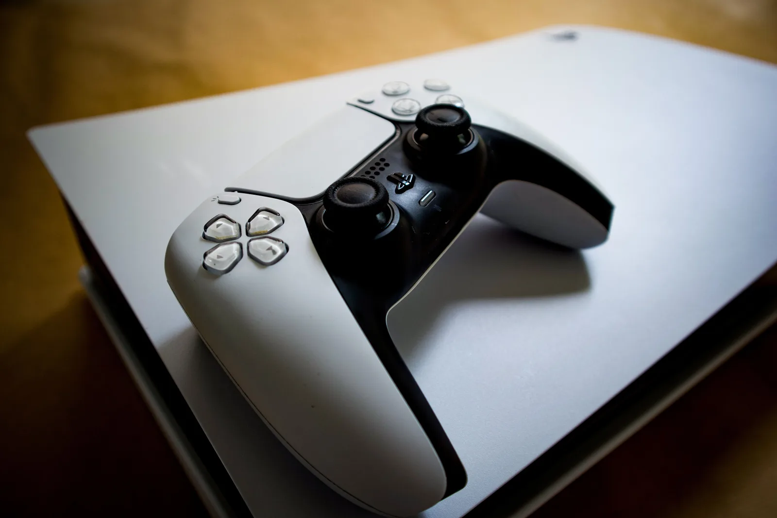 Máy PlayStation 5 và tay cầm DualSense đặt trên kệ gỗ