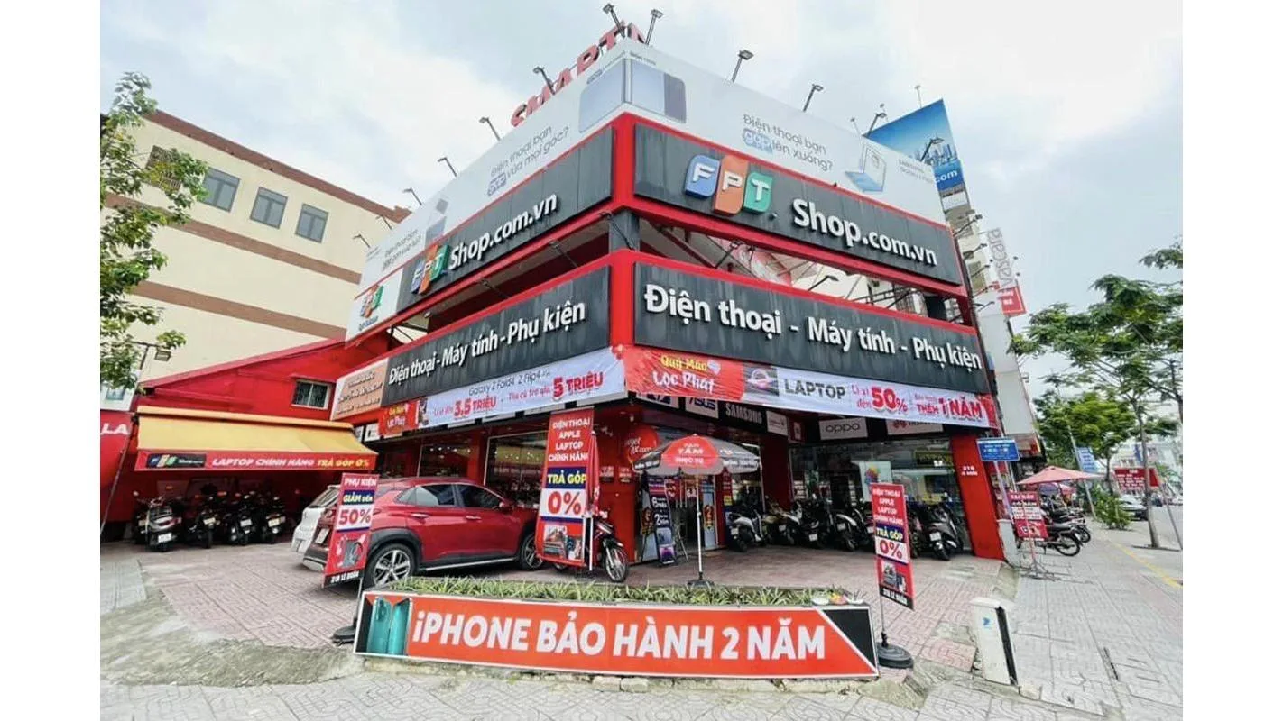 Mặt tiền cửa hàng FPT Shop 3 tầng màu đỏ-trắng với băng rôn iPhone bảo hành 2 năm
