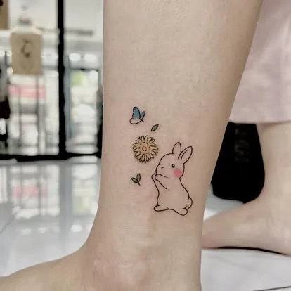 Hình xăm nhỏ chú thỏ và hoa cúc ở mắt cá chân, chụp tại San Tattoo